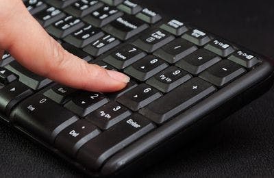 finger pressing numbers on a computer keyboard numpad