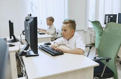 Boys are practicing typing on computer keyboards to get the touch typing benefits